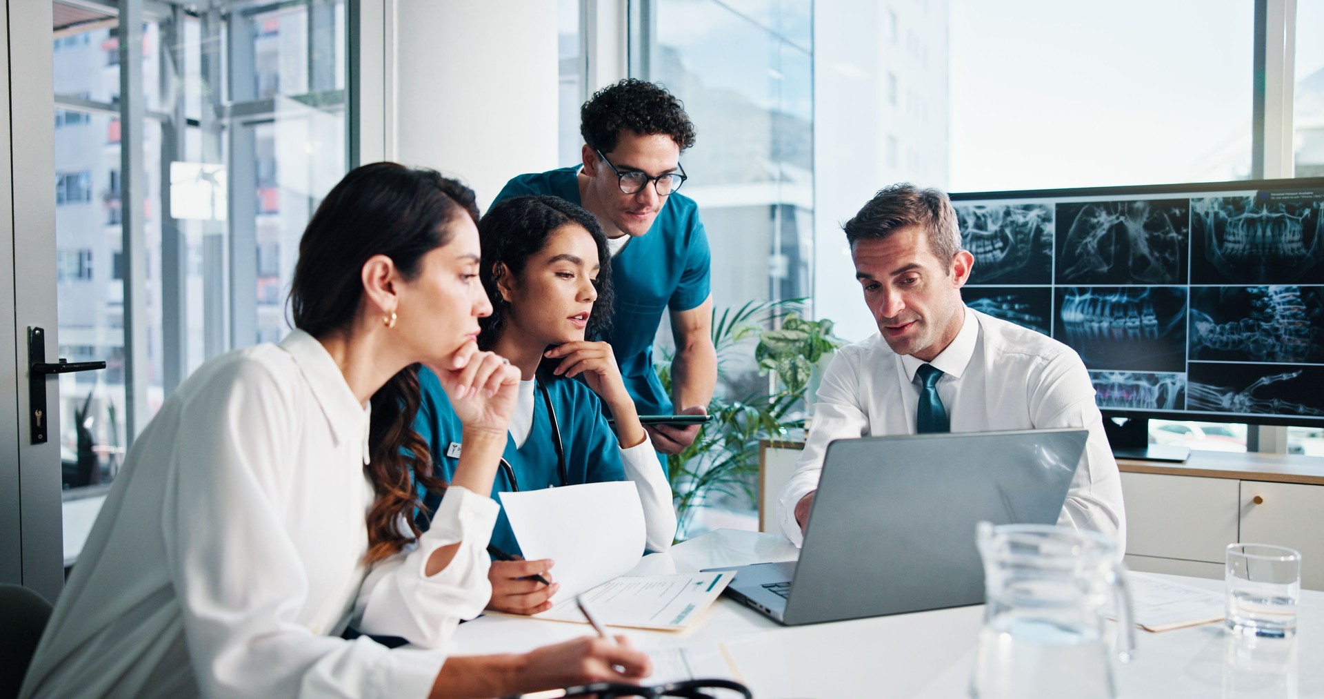 People, doctor and discussion with laptop for meeting, medical planning or procedure at hospital. Group, healthcare workers or employees with technology, documents or x ray screen for surgery results